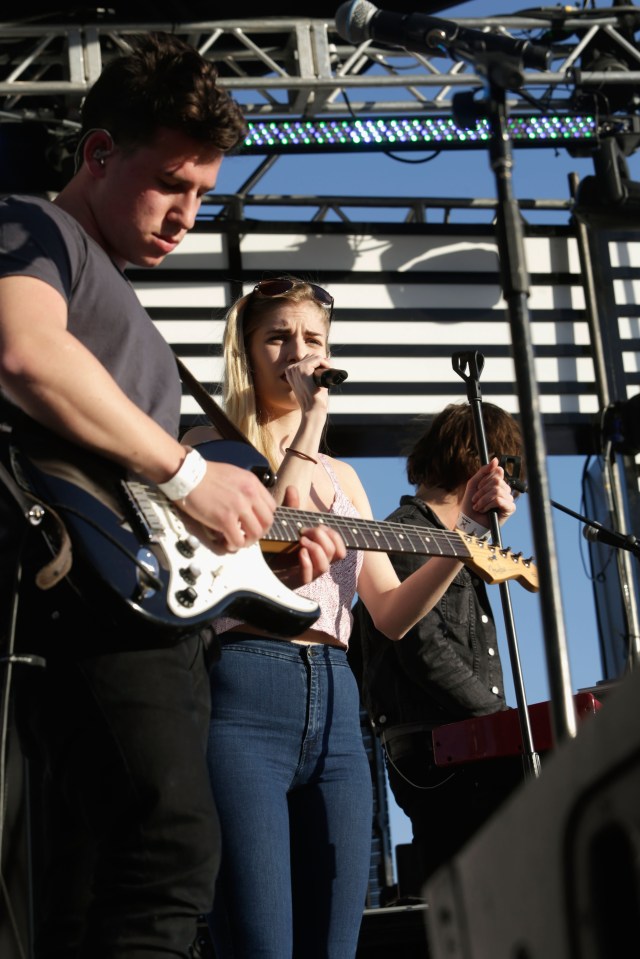 a woman singing into a microphone while a man plays a guitar