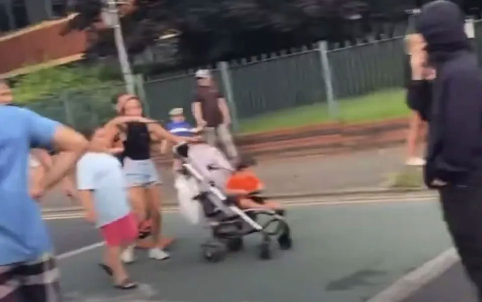 Nevey Smith pushes a child in a stroller during the disorder in Manchester