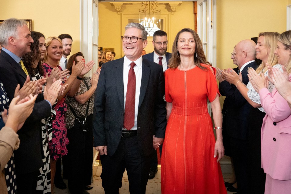 a man in a suit and tie stands next to a woman in a red dress