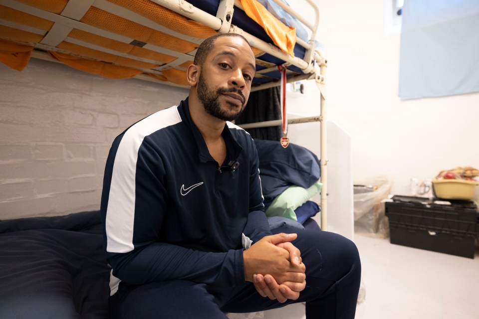 a man in a blue nike shirt sits on a bunk bed