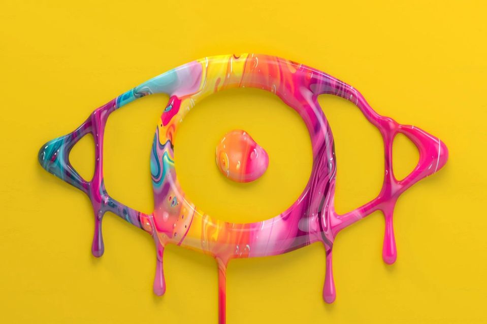 a colorful eye made out of paint on a yellow background