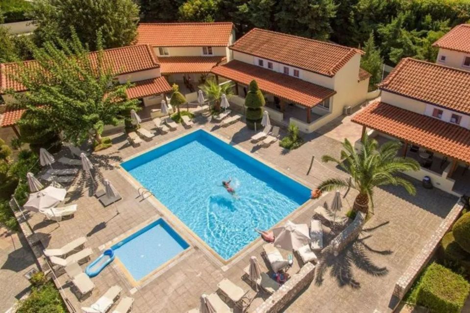 an aerial view of a swimming pool surrounded by chairs and umbrellas