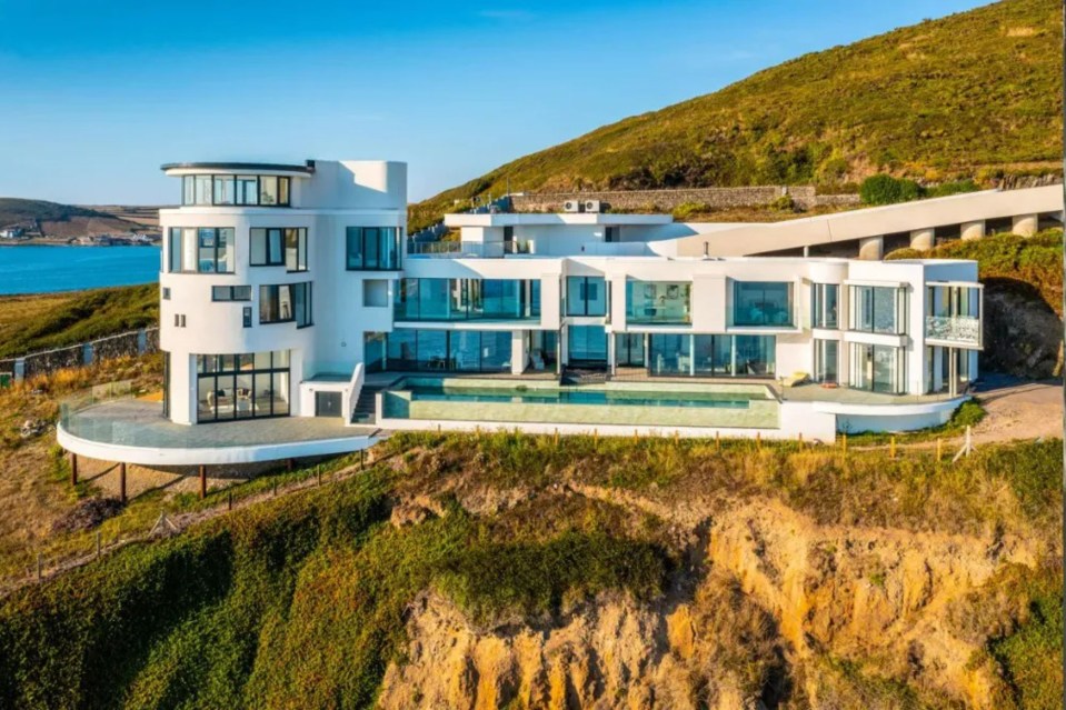 a large white house sits on top of a cliff overlooking the ocean