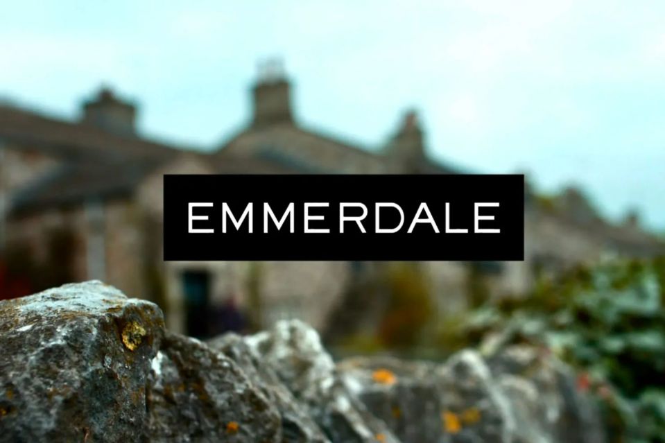 a sign that says " emmerdale " in front of a stone wall