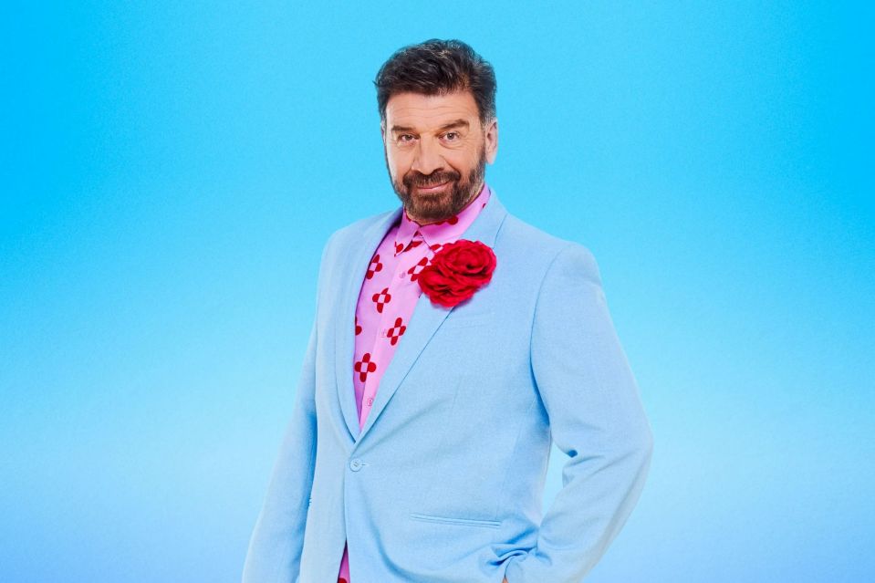 a man in a blue suit and pink shirt has a red flower in his pocket