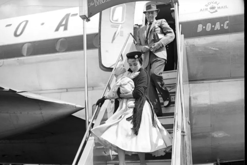 a black and white photo of two people boarding a royal air mail plane