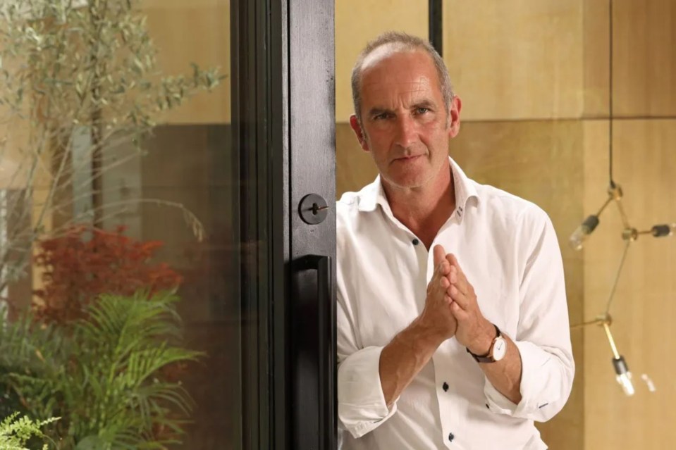 a man in a white shirt is standing in front of a glass door