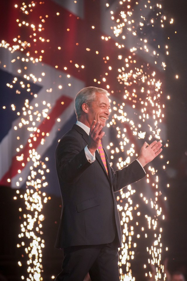 a man in a suit stands in front of a fireworks display