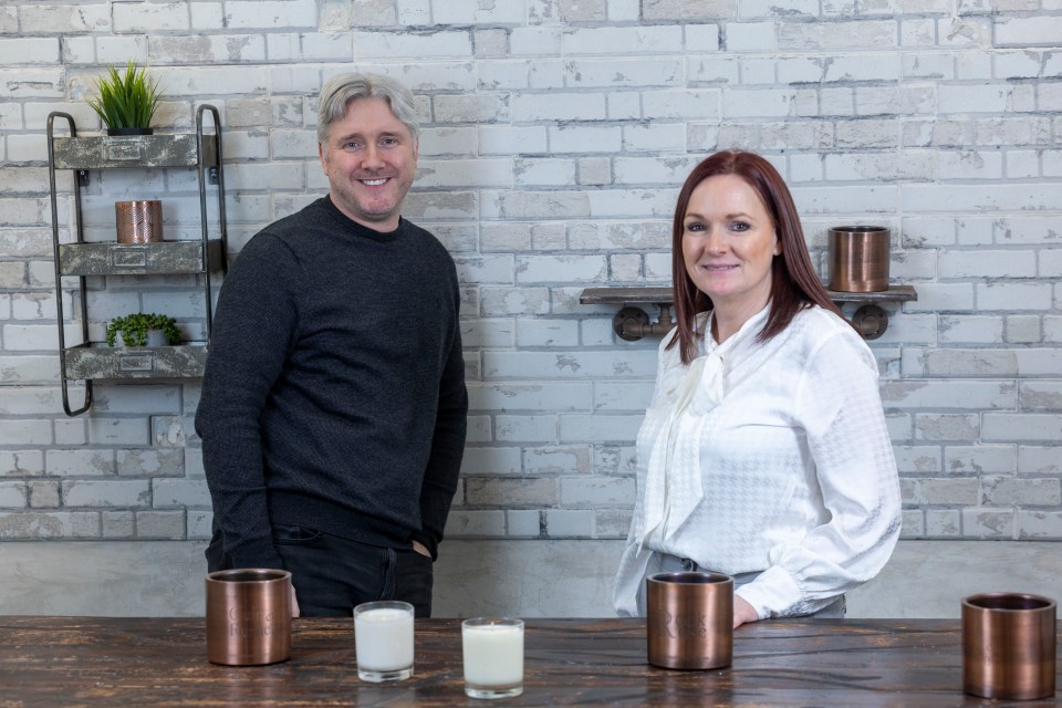 a man and a woman standing next to a table with candles on it