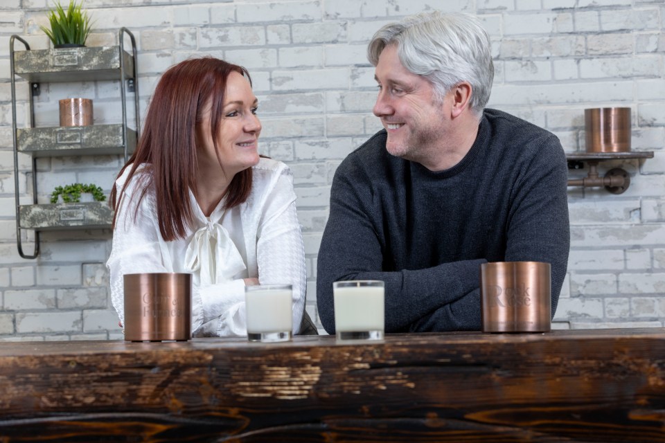 a man and a woman sit at a table with candles on it