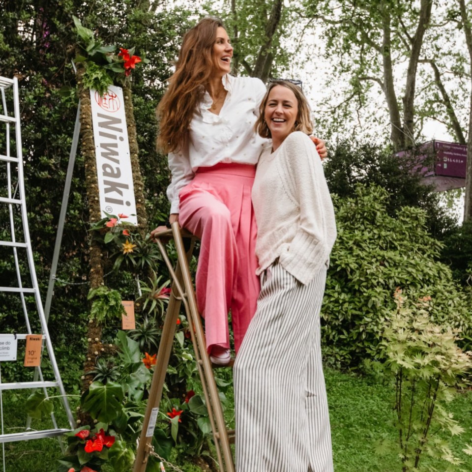 two women standing next to a sign that says niwaki