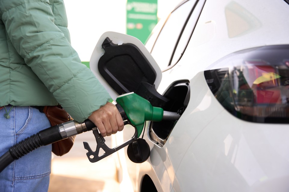 a person is pumping gas into a white car