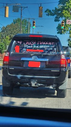 a black suv with a sign on the back window that says `` just married fund our honeymoon '' .