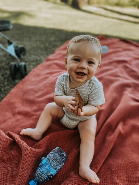 a baby is sitting on a blanket next to a bottle of aquafina water