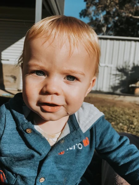 a baby wearing a blue sweater with the word o on it