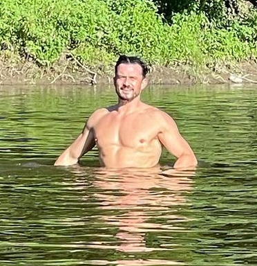 a shirtless man is standing in a body of water .