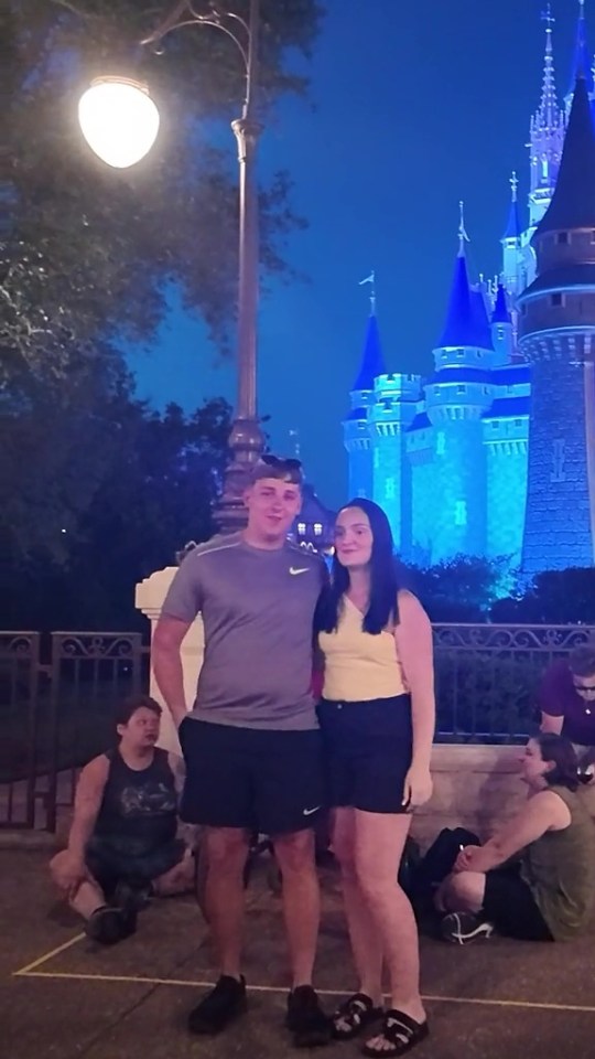 a couple standing in front of a castle at night