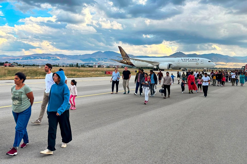 Passengers disembark the plane after the bomb threat