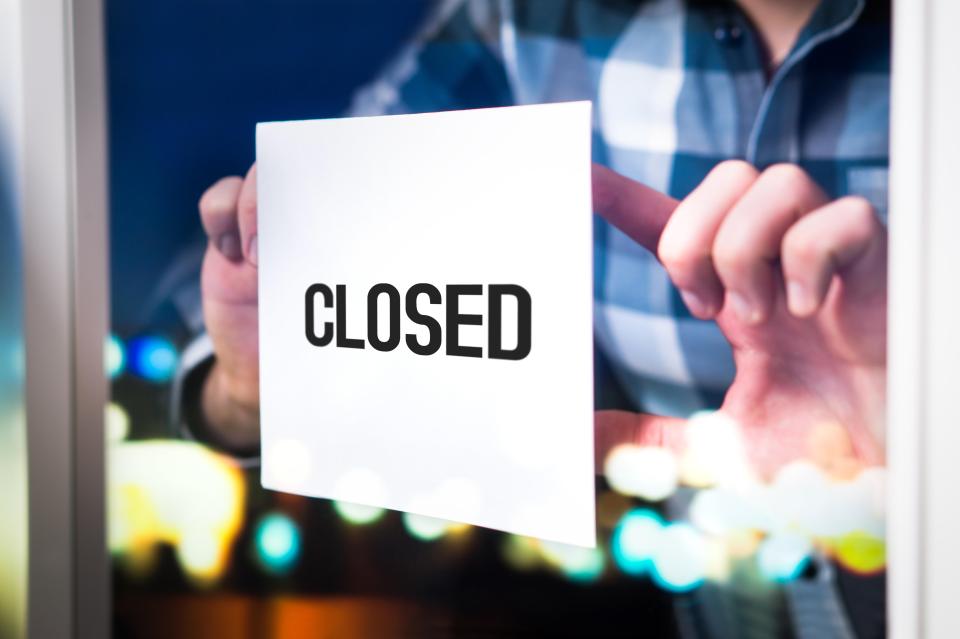 a person is holding a sign that says closed