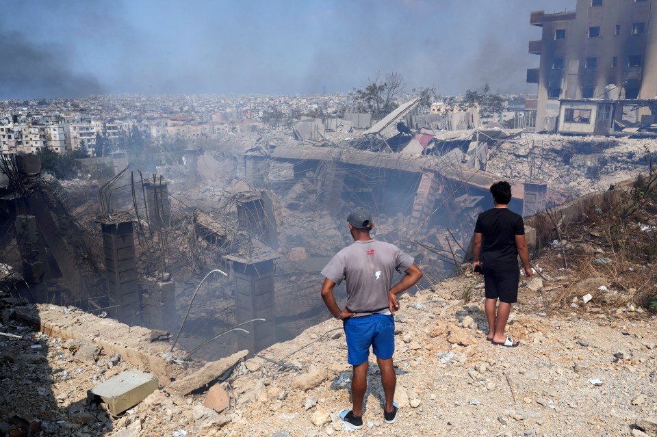 Citizens look over at a collapsed crater in the ground following an airstrike