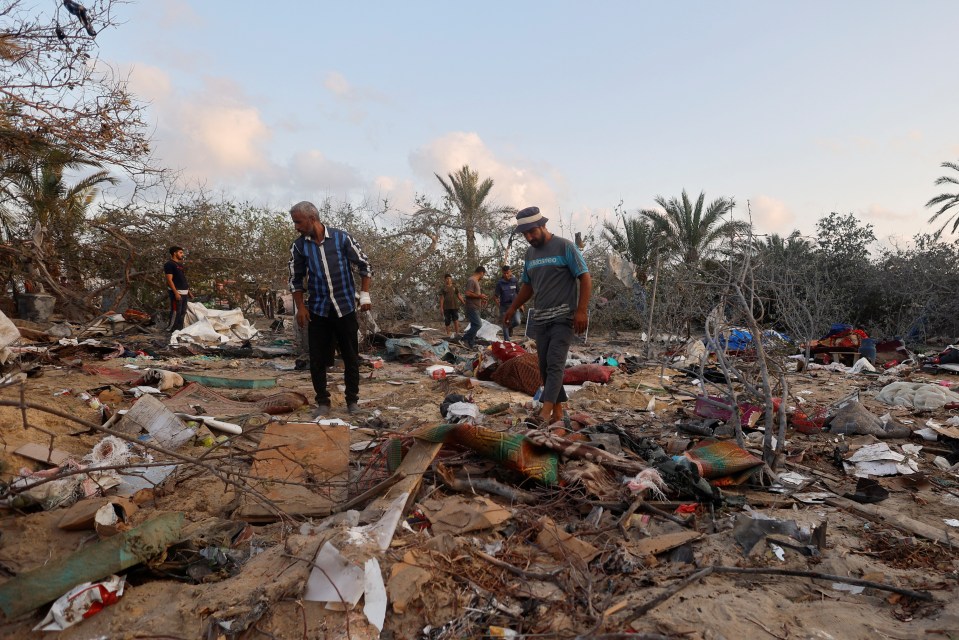 People inspect the site following strikes on the camp this morning