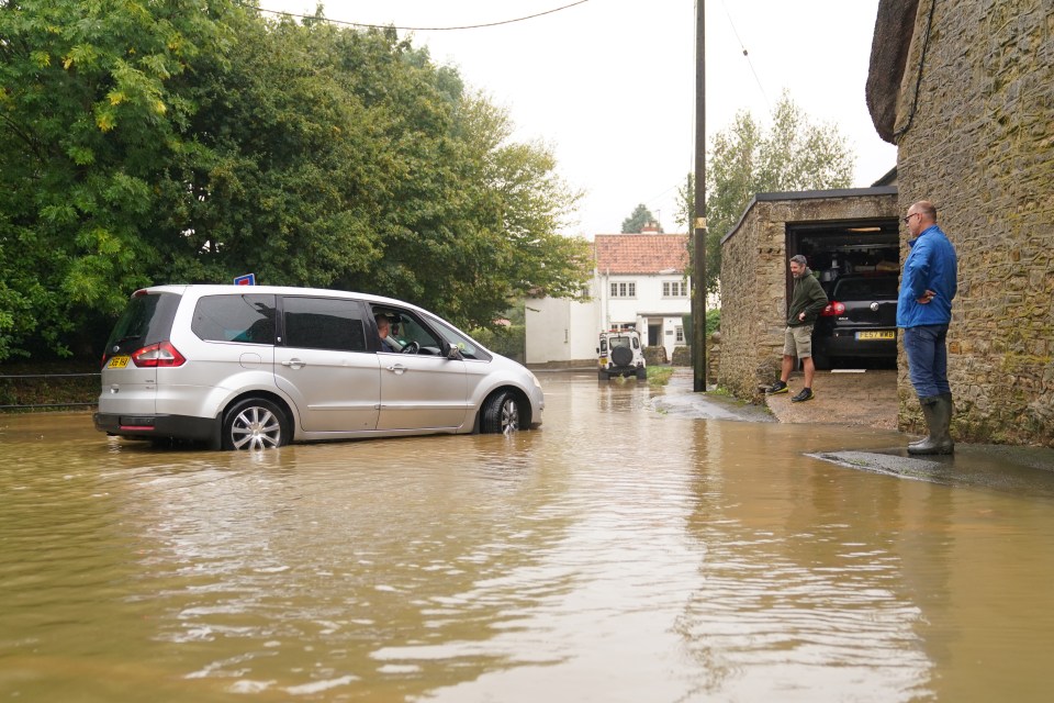 People looking at a car in flood water, also in Grendon