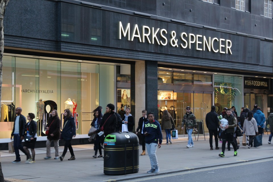 people walking in front of a marks & spencer store