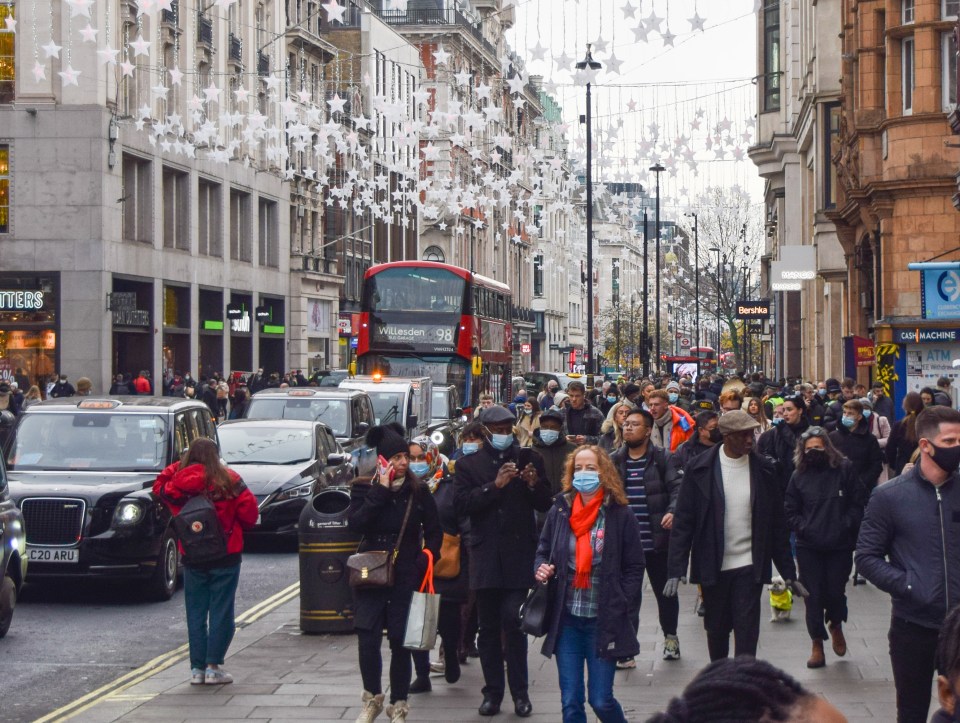 a red double decker bus is driving down a busy street