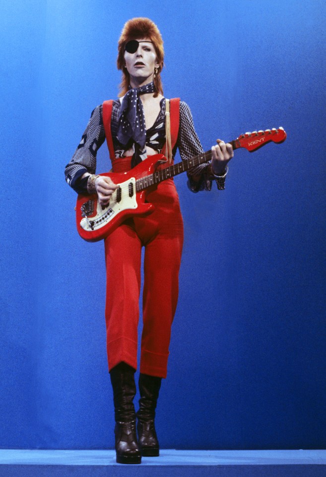 a man in red pants is playing a red hardy guitar