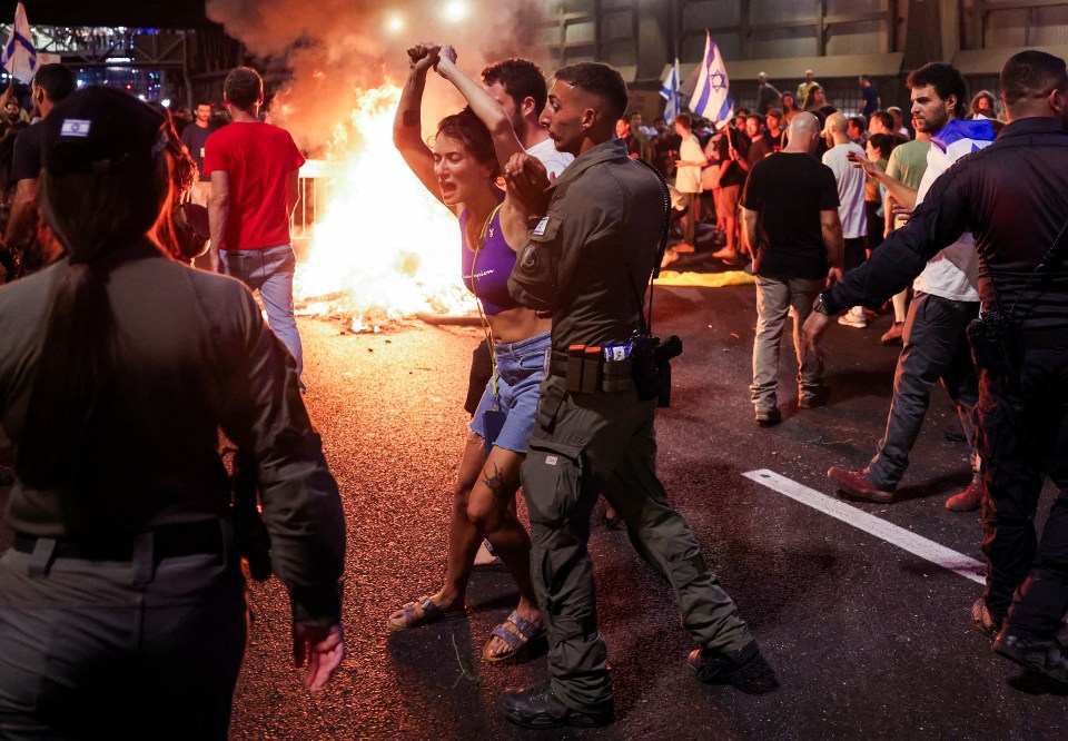 A woman is dragged away by officials in Tel Aviv, Israel on Sunday