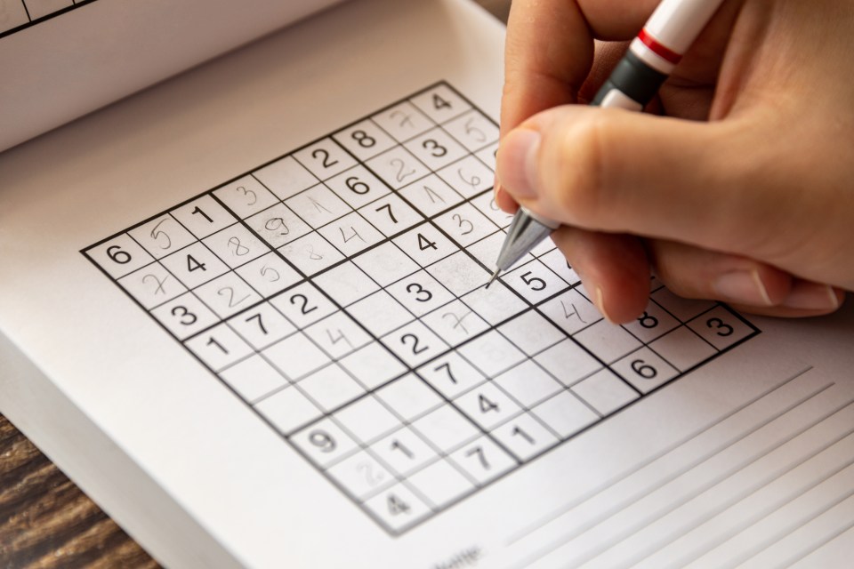 a person is using a pen to solve a sudoku puzzle