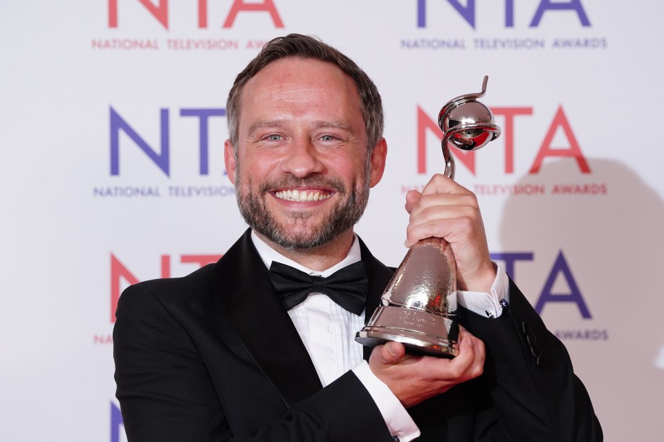 a man holding a trophy in front of a sign that says national television awards