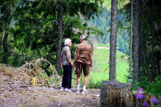 a man and woman standing in the woods holding hands