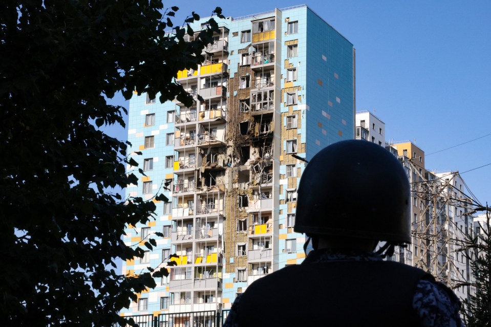 a man in a helmet stands in front of a blue and yellow building