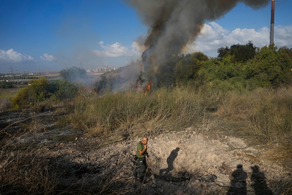 A police officer inspects the area around the fire near the crater