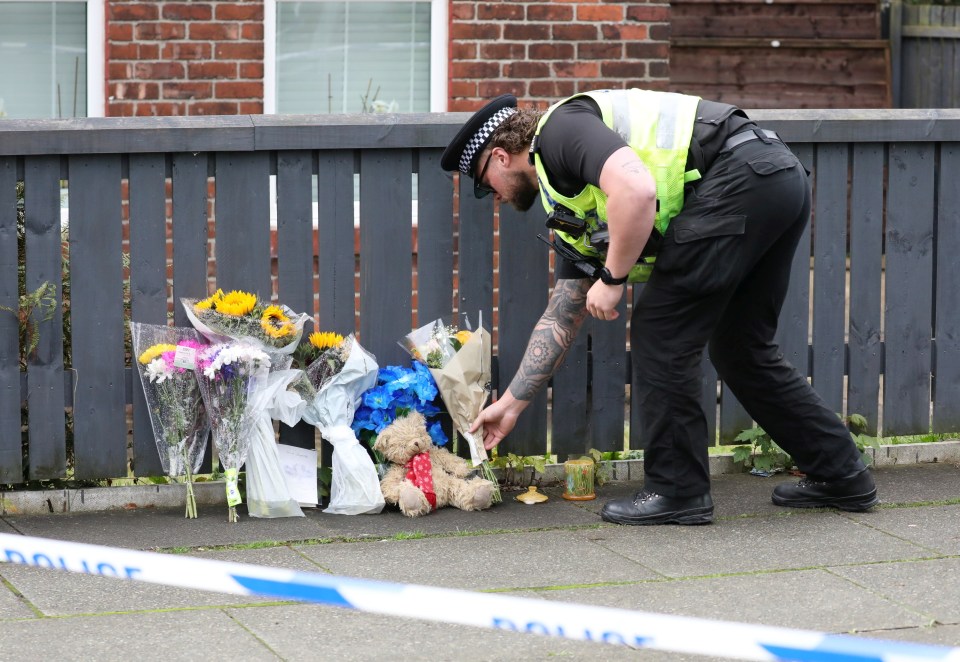 Police and floral tributes at the scene in South Radford Street, Salford