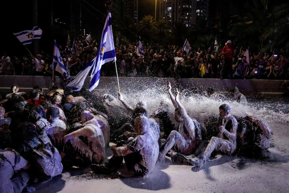 Police in Tel Aviv spray protestors sitting in the middle of a road with a water cannon on Sunday