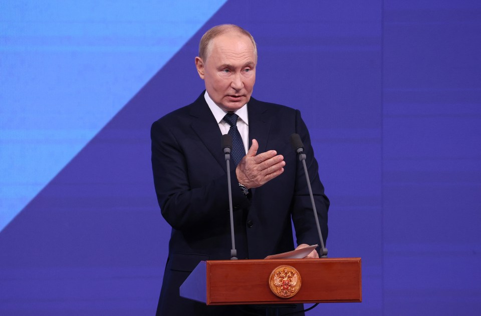 a man in a suit and tie stands at a podium with two microphones