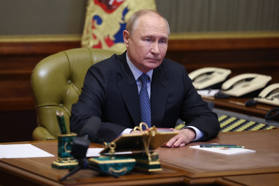 a man in a suit and tie sits at a desk