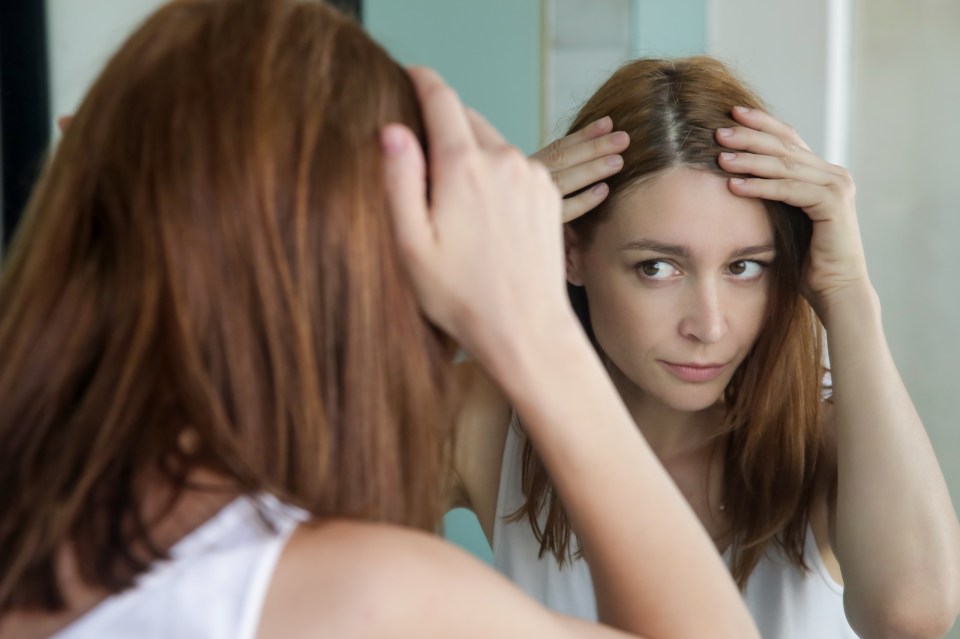 a woman is looking at her hair in a mirror