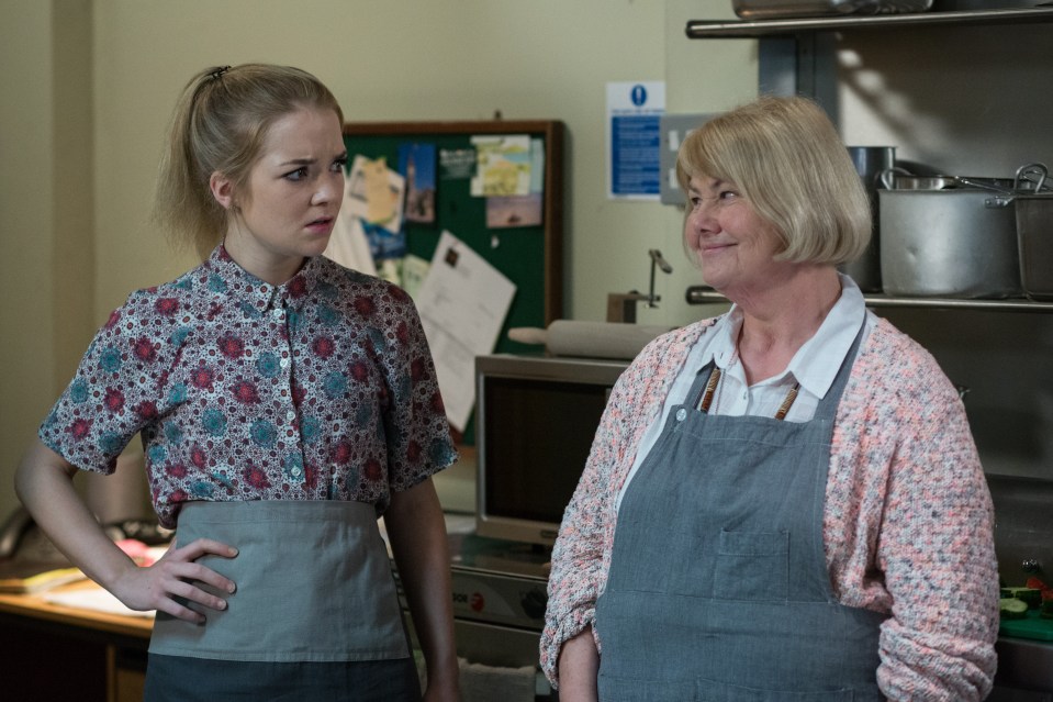 two women standing next to each other in front of a microwave