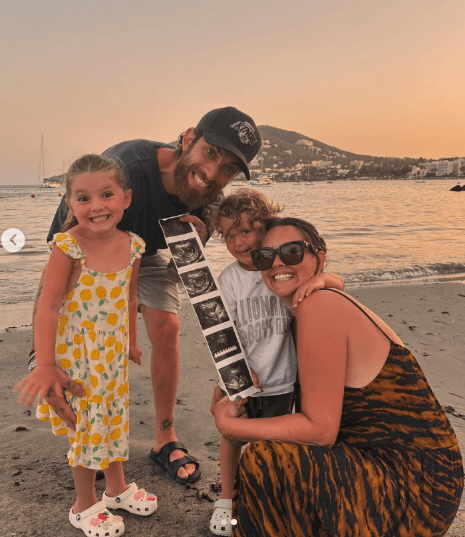 a family posing for a picture on the beach with a man wearing a shirt that says lions boys