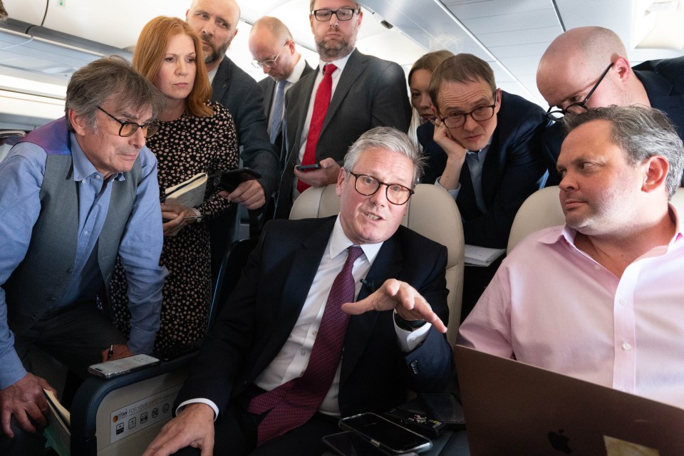 a group of people on an airplane looking at a laptop