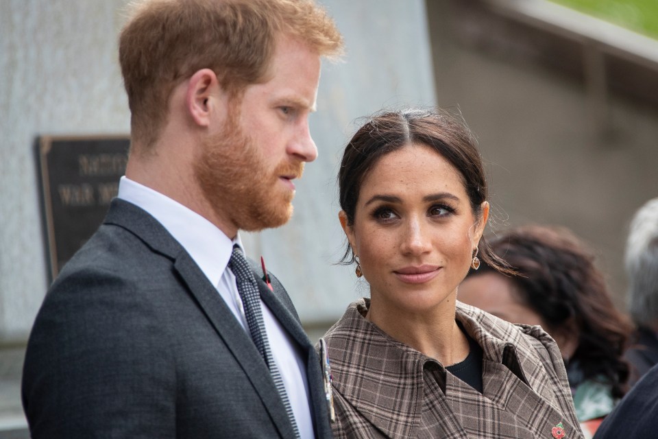 a man in a suit and tie stands next to a woman in a plaid coat