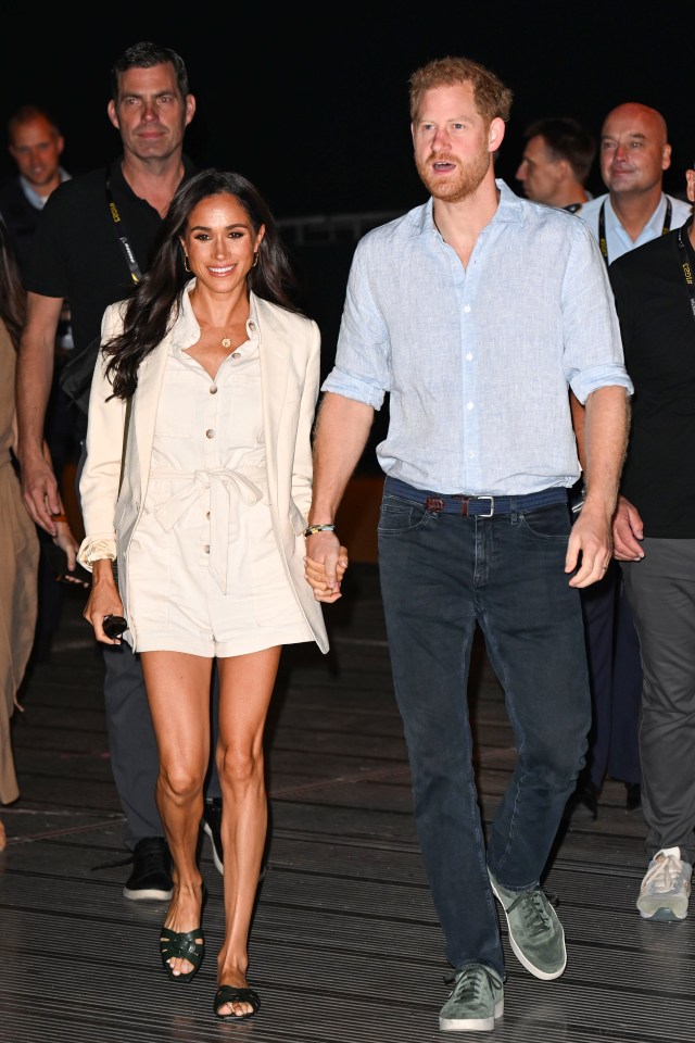 prince harry and meghan markle are walking down a street holding hands