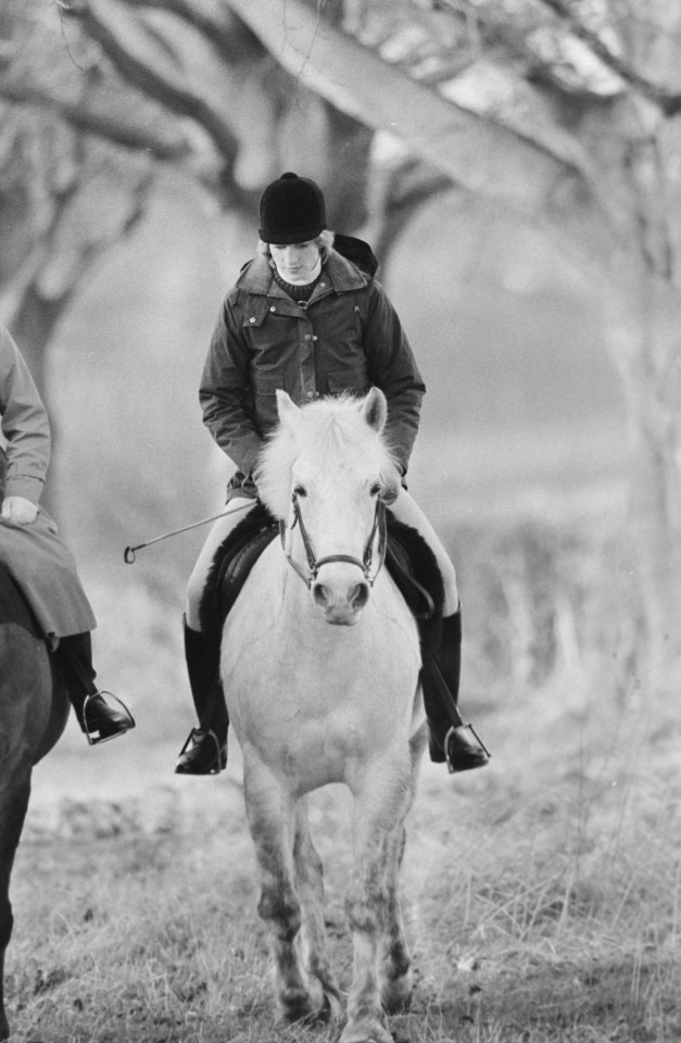 a black and white photo of a woman riding a white horse