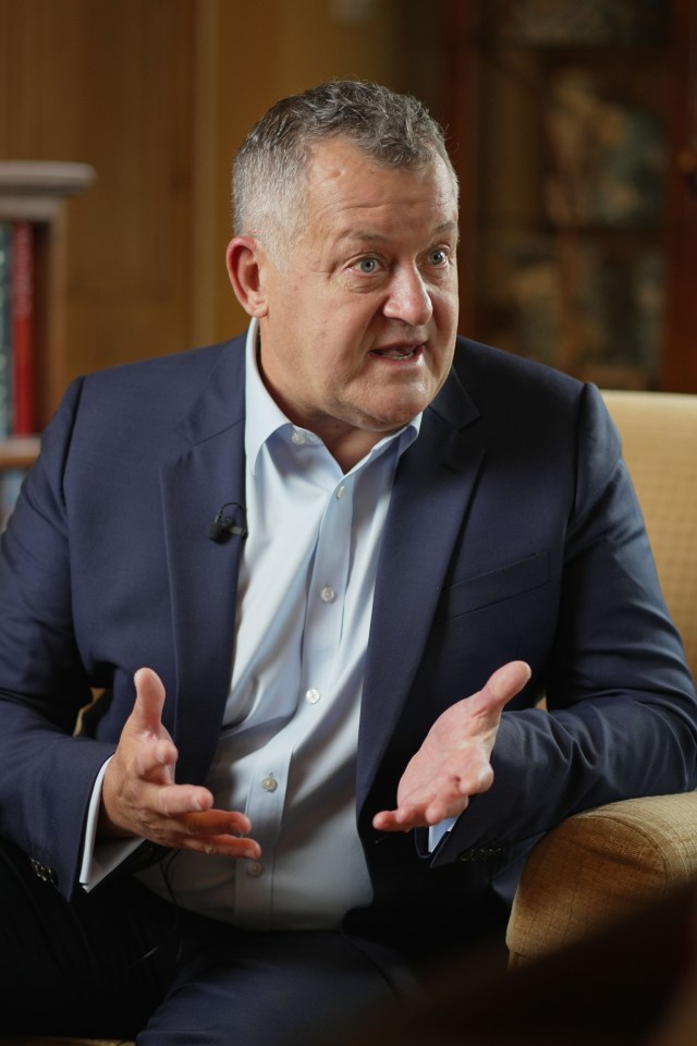 a man in a suit is sitting in a chair with his hands outstretched