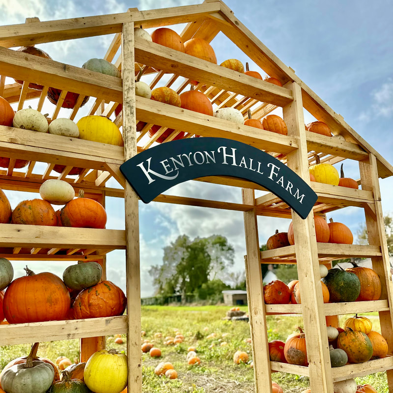 a sign for kenyon hall farm surrounded by pumpkins