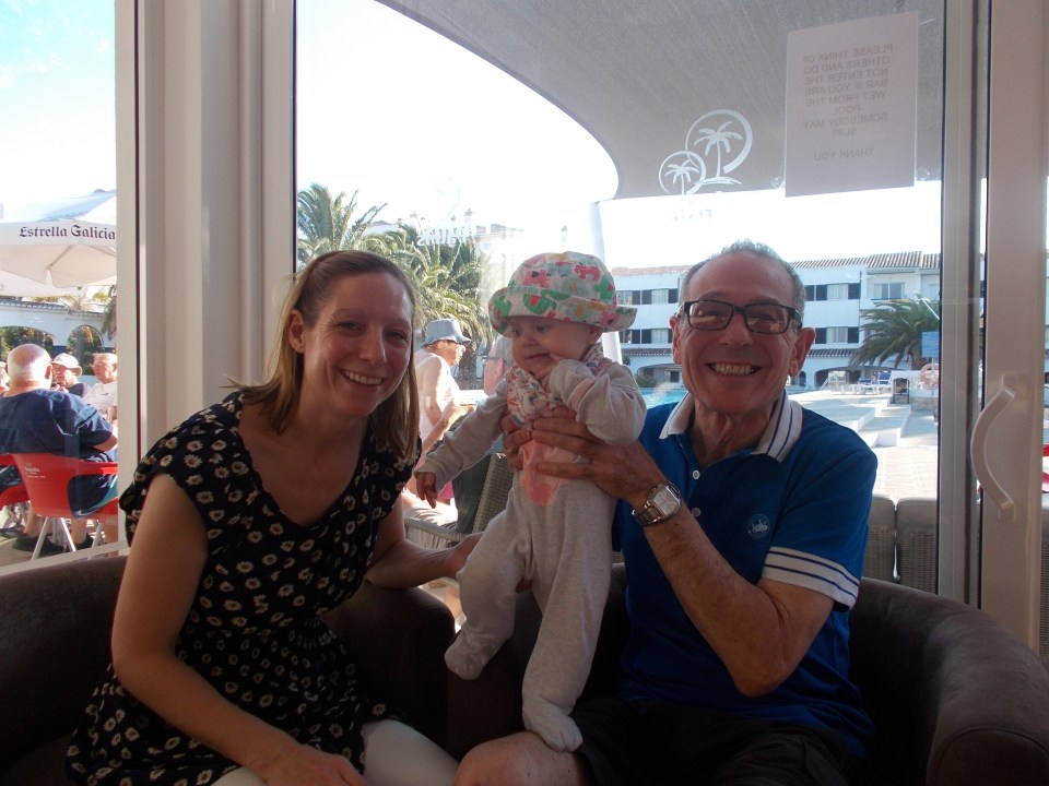 a man and woman holding a baby in front of a sign that says estrella galicia