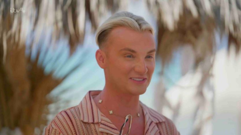 a man in a striped shirt is smiling in front of a palm tree